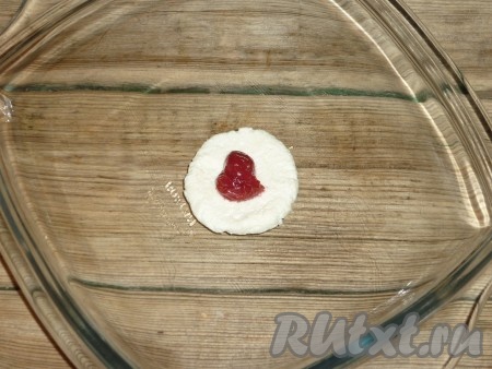 От творожного теста отрывать небольшие кусочки, разминать их в кружки, в центр выкладывать по вишенке.