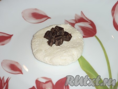 Полученную однородную творожную массу разделить на 10 равных частей. Каждую часть размять в лепешку, на середину которой выложить шоколад (можно выложить целые кусочки шоколада, а я решила измельчить шоколадку ножом, чтобы легче было формировать сырники).
