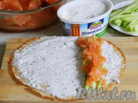 На блин намазать творожный сыр тонким слоем. Выложить полоски огурцов и кусочки семги.