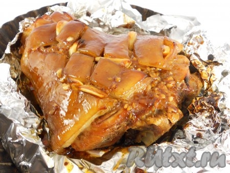 Накрыть рульку фольгой и отправить в предварительно разогретую до 180 градусов духовку на 1 час. После этого верхнюю фольгу убрать. Приготовить еще один соус: смешать оставшиеся: 1 столовую ложку меда, 1 столовую ложку соевого соуса, добавить томатную пасту, тщательно перемешать до однородного состояния. Смазать верх рульки половиной этого соуса и запекать в духовке при 200 градусах 15-20 минут. Далее рульку снова также смазать оставшимся соусом и продолжать запекать при той же температуре еще 15-20 минут. Рулька должна стать очень красивого бронзового цвета с ярким блеском.
