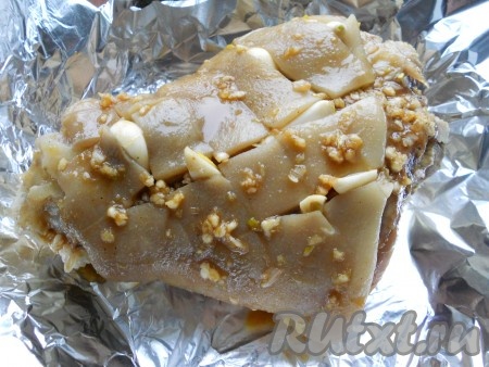 Рульку выложить в форму для запекания, застеленную фольгой в 2 слоя, и хорошо смазать ее подготовленным соусом. Каждый из оставшихся зубчиков чеснока разрезать на 2 части и вложить в надрезы.
