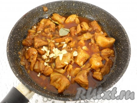 Дать жидкости в сковороде закипеть, уменьшить огонь. Сковороду прикрыть крышкой и тушить свинину в красном вине на медленном огне минут 30-40 (до мягкости мяса), периодически перемешивая. Если нужно, добавить в процессе тушения ещё немного воды. В конце тушения добавить в сковороду лавровый лист, измельчённый чеснок и немного чёрного молотого перца, перемешать, протушить ещё минут 10 и убрать с огня.