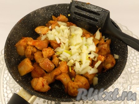 В сковороде разогреть растительное масло, выложить кусочки свинины. Обжарить мясо на среднем огне в течение 3-4 минут, периодически перемешивая. Далее добавить в сковороду очищенный и нарезанный на небольшие кусочки лук, перемешать. Обжаривать свинину с луком в течение 4-5 минут (до мягкости лука), иногда перемешивая.