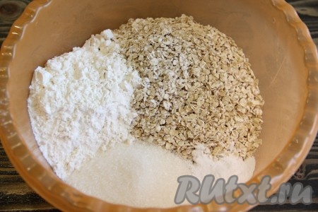 В глубокую миску просеять муку, добавить сахар, разрыхлитель и овсяные хлопья.