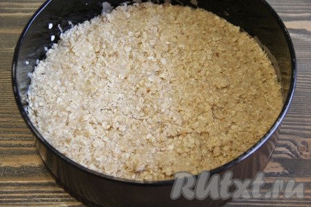 Полученную овсяную массу разделить на две части. Одну часть массы выложить в форму для выпечки (я использовала разъёмную форму диаметром 22 сантиметра). Разровнять массу и слегка утрамбовать.