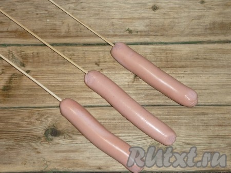 Обвалять сосиски в пшеничной муке, чтобы с них не стекал кляр. Насадить сосиски на деревянные палочки.&nbsp;