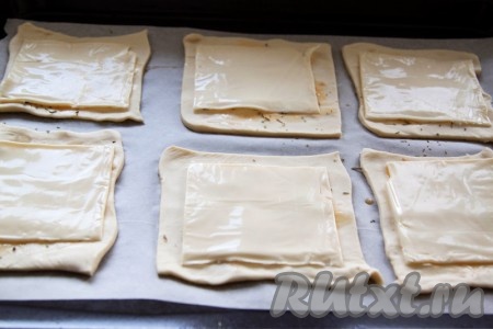 Уложите на квадраты теста слайсы сыра.