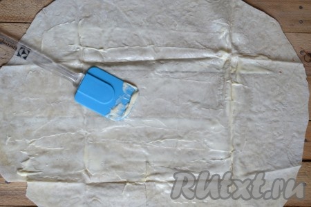 Листы лаваша расстелить на столе и, немного отступив от краёв, смазать поверхность тонким слоем сметаны (или майонеза).