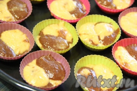 Выложить два вида теста в формочки, чередуя белое и коричневое тесто, заполняя формочки на 1/2 объёма. 