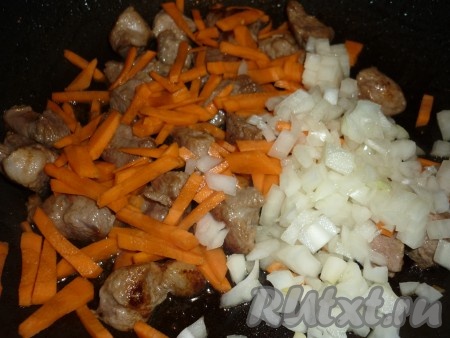 Затем огонь уменьшить, свинину посолить, поперчить, добавить нарезанные лук и морковь и, помешивая, жарить 2-3 минуты. 
