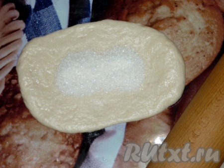 Каждую часть теста на присыпанной мукой поверхности раскатать в овал толщиной 0,5 сантиметра. В центр овала насыпать 1 чайную ложку сахара.
