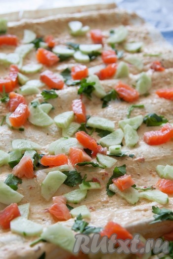 Разложите лаваш и смажьте его соусом. Нарежьте огурец и рыбу маленькими кусочками и разложите на лаваше. Нашинкуйте зелень и разложите там же.