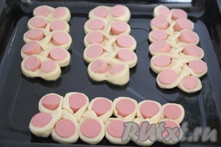 Противень для выпекания смазать растительным маслом. Выложить сосиски в тесте на противень и оставить в тёплом месте на 30-40 минут, прикрыв полотенцем. 
