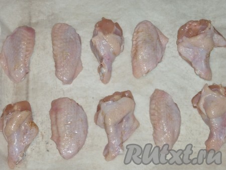 По прошествии времени выложить куриные крылья на противень, застеленный пергаментом, и отправить в духовку, разогретую до 180 градусов, на 15 минут.