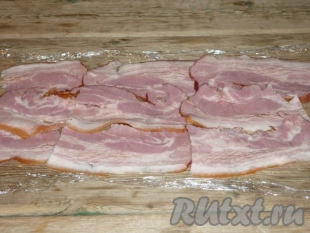 Пищевую плёнку разложить на стол, выложить внахлест ломтики ветчины (или бекона).&nbsp;
