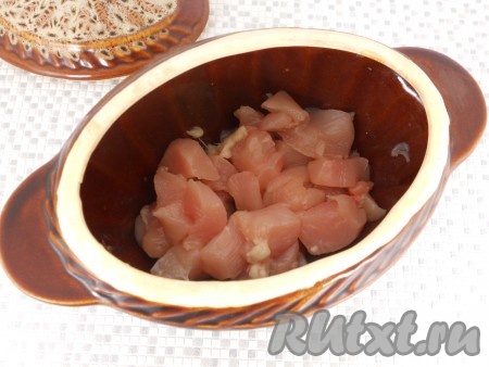 В горшочек влить растительное масло, выложить нарезанное небольшими кусочками куриное филе.
