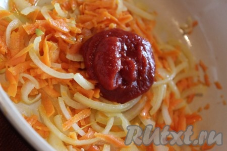 В глубокую сковороду влить немного растительного масла, добавить нарезанный полукольцами лук. Обжарить лук до золотистого цвета на среднем огне, примерно 3-5 минут, не забывая помешивать. Затем в сковороду к луку добавить натертую морковь и хорошо перемешать. Обжарить овощи, иногда помешивая, в течение нескольких минут. Затем в сковороду к овощам добавить 3 чайных ложки томатной пасты. Все еще раз хорошо перемешать.
