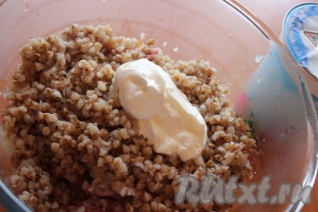 Далее в миску с фаршем добавить отварную гречневую крупу и 2 столовых ложки сметаны.
