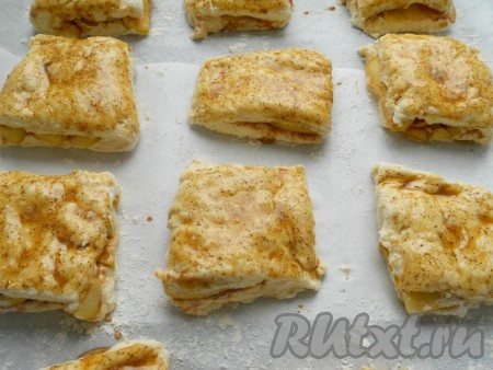 Накрыть яблоки второй частью теста и придавить края. Разрезать тесто с яблоками на 9-12 частей (квадратов), поместить их на присыпанный чуть мукой противень (я застелила пергаментом). Смазать булочки подготовленной смесью.