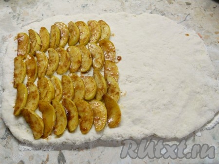 Далее на присыпанной мукой поверхности растянуть руками тесто, придав ему форму прямоугольника (тесто очень пластичное) толщиной около 1 см. На одну сторону теста выложить дольки яблок без соуса (лишняя жидкость не нужна, соус понадобится для подачи булочек).
