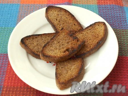 Обжарить кусочки хлеба на растительном масле на разогретой сковороде с одной стороны. Ещё горячие кусочки хлеба натереть чесноком. Я обжариваю кусочки хлеба только с одной стороны, но если вам нравятся более хрустящие бутерброды, то можете обжаривать хлеб с обеих сторон - это дело вкуса. Можно также подрумянить хлеб в тостере.