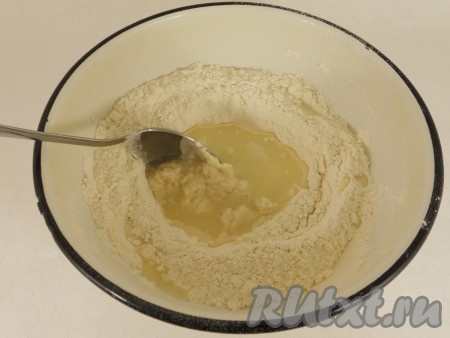 Сыворотку смешать с водой. В мучной смеси сделать углубление и частями вливать смесь сыворотки и воды, замешивая тесто.