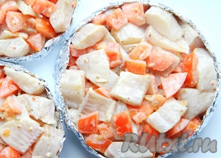 Теперь добавляем к маринованной тилапии нарезанные помидоры, аккуратно перемешиваем и выкладываем поверх лука.
