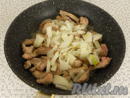 Сковороду разогреть с растительным маслом, выложить мясо и обжаривать его на довольно сильном огне до небольшой румяной корочки, иногда перемешивая. Далее добавить к свинине нарезанный репчатый лук. Обжаривать все вместе минут 5-7 на среднем огне.
