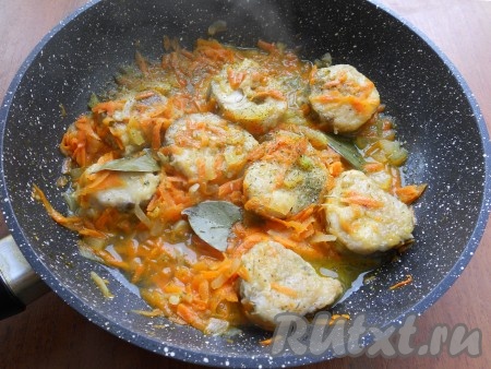 Влить горячую воду, добавить лавровый лист и тушить рыбу вместе с овощами под прикрытой крышкой на медленном огне 15 минут.
