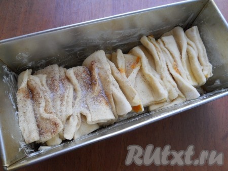 Прямоугольную форму для кекса смазать сливочным маслом и выложить все части вертикально, не прижимать слишком друг к другу. Части получатся не ровными, но это придаст булочкам интересный вид. Складывать тесто так: половина - коричные, половина - апельсиновые. Сверху коричную часть посыпать немного корицей, а апельсиновую - полить чуть апельсиновым соком и обе части посыпать сахаром.
