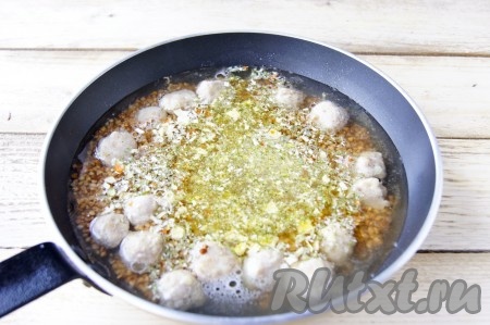 Добавить 2,5 стакана горячей воды, соль, чёрный молотый перец, специи, перемешать. В качестве специй я использовала универсальную приправу, в её состав входит соль, поэтому солить я не стала. Дать воде закипеть, накрыть сковороду крышкой, убавить огонь и готовить гречку с фрикадельками минут 20-25 (до полного испарения жидкости).