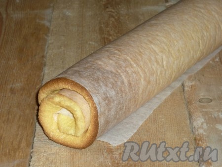 Скрутить бисквит рулетом прямо в пергаменте. Оставить на 5 минут. 