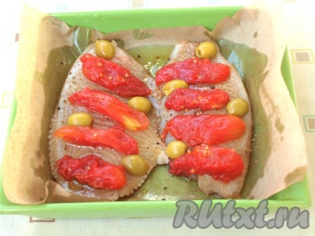 Филе тилапии выложить в форму для выпечки, застеленную пергаментом. Сверху присыпать рыбу перцем и небольшим количеством соли (не пересолите, ведь тилапия мариновалась в соевом соусе, а он достаточно солёный). Вылить на тилапию остатки маринада. Поверх рыбы выложить половинки оливок и нарезанные помидоры.