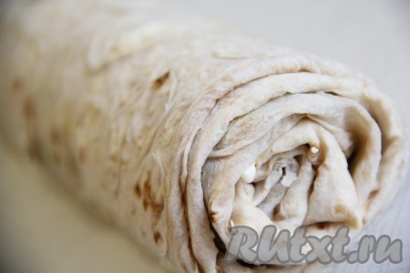 Завернуть края лаваша на начинку и свернуть лаваш с начинкой в плотный рулет, начиная с широкой стороны. Завернуть рулет в пергаментную бумагу (или пищевую плёнку) и дать настояться 1 час. Лучше убрать в холодильник.