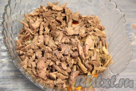 Затем добавить шампиньоны и куриную печень. Посолить салат и хорошо перемешать.