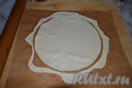 По прошествии минимум 4 часов можно начинать выпекать коржи. Из холодильника доставать по одному кусочку и раскатывать в круг немного больше желаемого диаметра (удобнее всего раскатывать коржи сразу на пергаменте или силиконовом коврике, и на нем же выпекать). Чтобы придать идеальную форму, положите на корж тарелку и обрежьте излишки, но не убирайте их, они пойдут на присыпку готового торта.