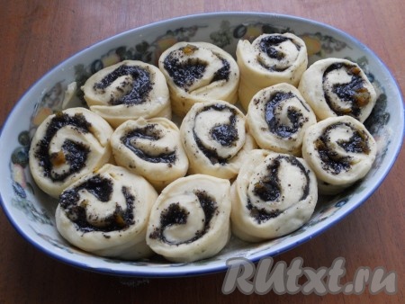 Свернуть в рулет и разрезать на части длиной около 5-6 см. Форму для выпечки смазать сливочным маслом и немного присыпать мукой. Выкладывать в форму рулетики вертикально.