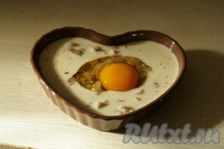 Сверху аккуратно разбить яйцо, не повредив желток. 