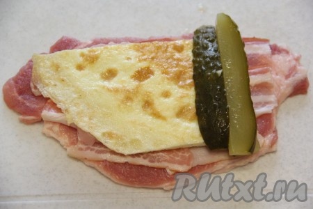 Затем выложить кусочек омлета и несколько брусочков огурца.