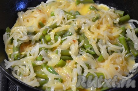 Поверх рыбы выложить спаржевую фасоль и лук (в зависимости от состава овощей, которые Вы используете, они будут добавляться на сковороду к рыбе либо сырыми, либо слегка обжаренными, либо, как фасоль, слегка отваренными). Залить яйцами. Накрыть крышкой, огонь уменьшить до минимума. Жарить до готовности, примерно 10 минут.
