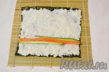 Затем выложить на рис начинку: несколько кусочков рыбы и огурца.&nbsp;
