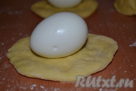 Каждый кусочек раскатать в лепешку, в центр лепешки выложить очищенное вареное яйцо (можно взять перепелиные, но тогда лепешки делайте меньшего размера).
