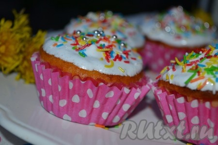 Тесто хорошо перемешать и наполнить им формы для маффинов, заполняя на 2/3 объёма. Отправить&nbsp;на 20-25 минут в духовку, разогретую до 180 градусов. Пока выпекаются маффины, приготовим белковую глазурь для украшения: яичный белок взбить (он должен увеличиться в объёме в 2-3 раза), затем постепенно всыпать сахарную пудру&nbsp; и взбивать в течение 5 минут. Украсить верх готовых маффинов белковой глазурью и кондитерской посыпкой.
